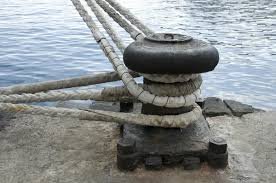 “Black mooring post secured to the shore with a rope.”